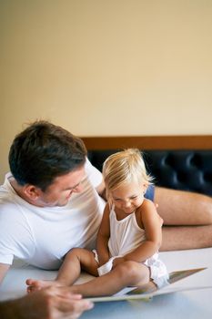 Laughing dad and little girl reading a book. High quality photo