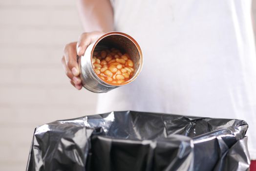 throwing tin container in a garbage bin .