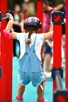 selective focus. Little girl child in protective clothing helmet knee pads elbow pads with rollers. girl 6 years old on the playground. crossfit for kids. Active girl goes in for traumatic sports.