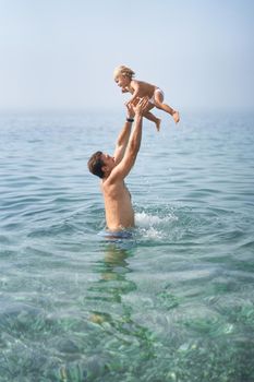 Dad throws a little girl into the sea. High quality photo
