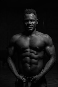 Portrait of an African American man with a naked torso in a dark studio. Muscular guy