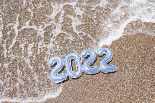 2022 numbers in the water on the golden sea sand. Beach season, borders open concept, summer vacation