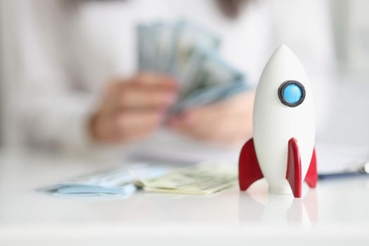 Close-up of rocket model on desk, rocketship symbol for startup, earn money on beneficial project. Success, growth, development, wealth, income concept