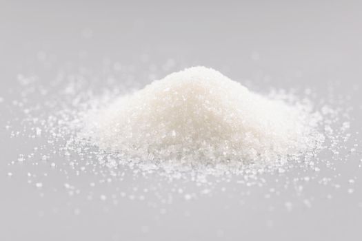Close-up of sugar crystals pile on grey background, heap of sweet powder, sugar substitute add in dishes or drinks. Ingredient, cooking, delicious concept