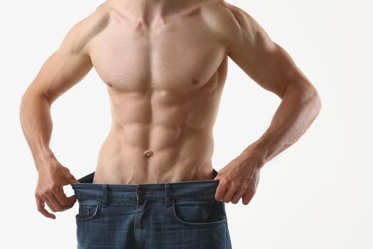 Close-up of fit man with muscles, show how big pants, slim body, perfect figure. Fitness trainer, professional model. Sport, modeling, wellness concept