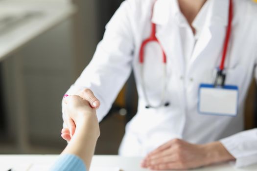 Close-up of doctor woman greet patient and shake hand, medical worker in uniform. Intern ready for appointment. Medicine, hello, nice to meet you concept