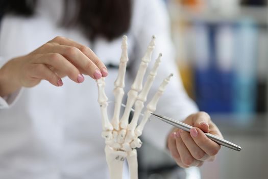 Close-up of female scientist explore human skeleton hand model, laboratory and medical anatomy science. Knowledge, education, lecture, biology, lab concept