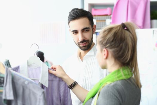 Portrait of female and male coworkers share ideas about new fashion collection. Talented dressmaker help costumer with choice. Store, mall, atelier concept