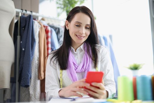 Portrait of brunette woman take order online, sell clothes over internet, promote website. Fashionable atelier with high quality garment. Business concept