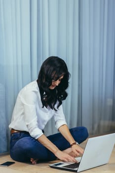 Woman working at home sitting on a podium in the room with laptop, business woman paper work talking on the phone