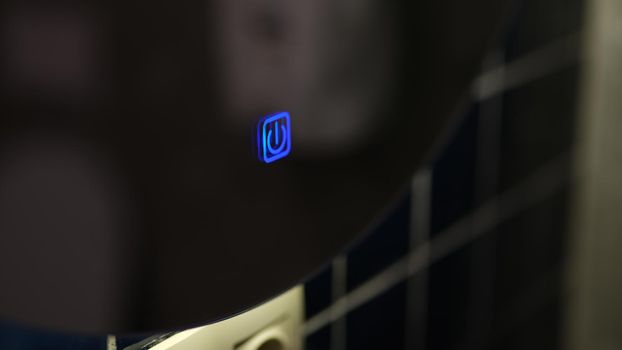 Blue button icon for turning on boiler in bathroom. Modern touch button on device concept