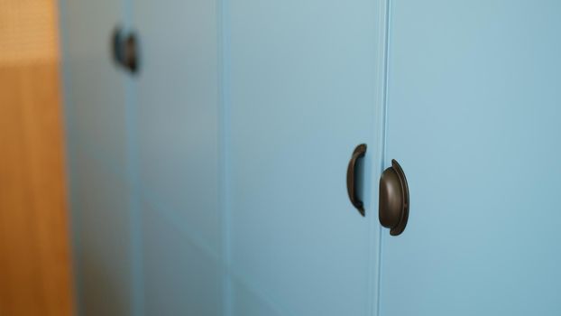 Blue sliding wardrobe with stylish reliable black handles for opening and closing. Modern black furniture handles concept