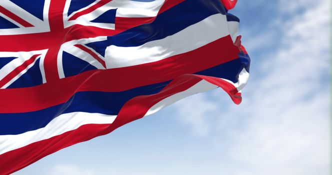 The US state flag of Hawaii waving in the wind on a clear day. Hawaii is a state in the Western United States, located in the Pacific Ocean. Democracy and independence. Seamless loop in slow motion