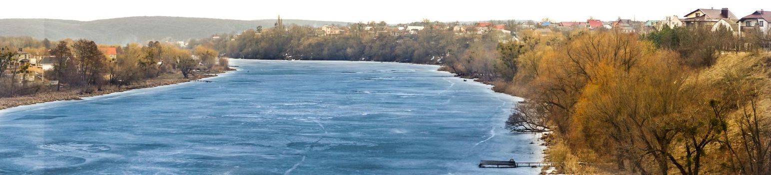 The river is covered with ice in winter. Panorama. Frozen water in the river. Beautiful landscape