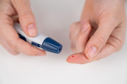 Caucasian woman doing a glucose test using a pen lancet