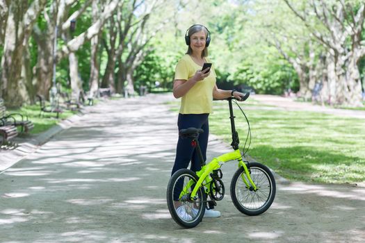 Active pensioner on a morning jog in the park, listening to music from headphones, looking at the phone camera and smiling, talking to friends via video link