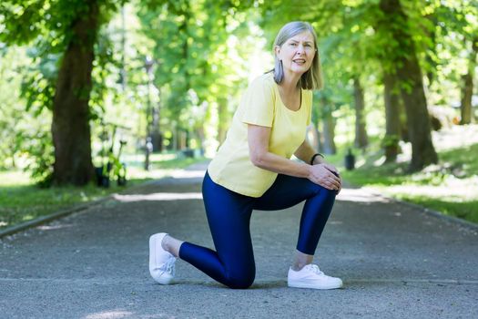 Trauma. Senior beautiful woman injured her knee. Holding her hands on her leg, she sat down. He goes in for sports and runs in the park.