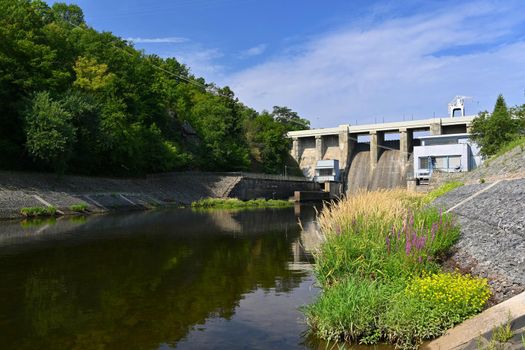 A dam on the Brno Reservoir by the Svratka River with a small power plant. Beautiful sunny summer day in nature.