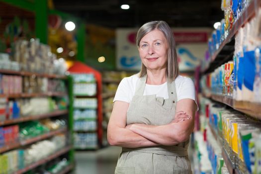 Portrait of happy senior woman grocery store employee with arms crossed smiling and looking at camera