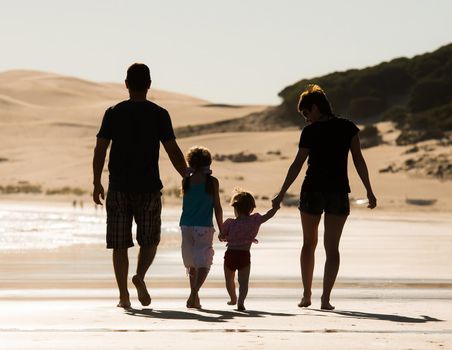 Silhouette of family, two adults and a child at the coast in sunset