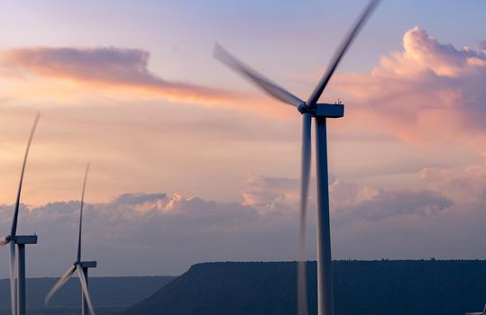 Wind energy. Wind power. Sustainable, renewable energy. Wind turbines generate electricity. Windmill farm on a mountain with sunset sky. Green technology. Renewable resource. Sustainable development.