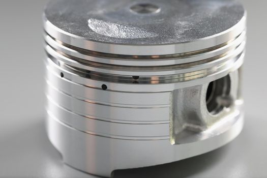 Close-up of silver metal part of car, detail for internal combustion engine placed on grey. Piston for automobile vehicle. Transport, component concept