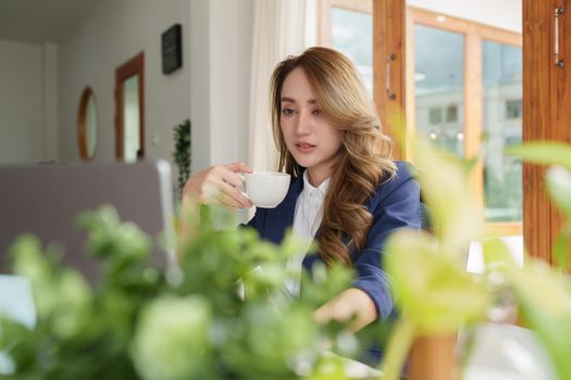 Attractive elegant owner is sitting at the table at workstation has online meeting with international business partners