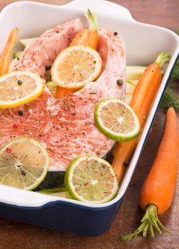 Steak of red fish and sliced lemons on white.