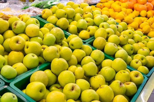 Pile of apples on the stall in the supermarket. Green apples in boxes on supermarket shelves.