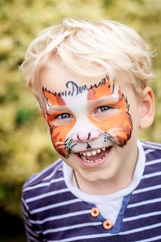 Cute happy and excited little boy with face paint. Face painting, kid painting face at the birthday party or on holidays