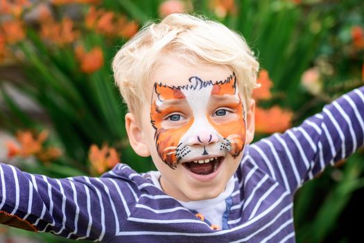 Cute happy and excited little boy with face paint. Face painting, kid painting face at the birthday party or on holidays