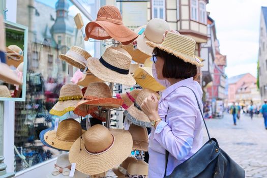 Woman tourist choosing to buy a straw hat in a store. Fashion, style, summer, holidays, shopping concept