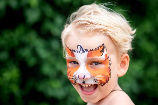 Cute happy and excited little boy with face paint. Face painting, kid painting face at the birthday party or on holidays