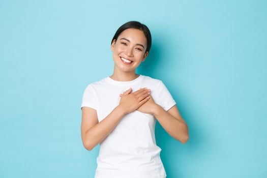 Lifestyle, beauty and shopping concept. Portrait of touched and grateful pretty asian girl thanking for flattering compliment, holding hands on heart and smiling with caring, tender expression.