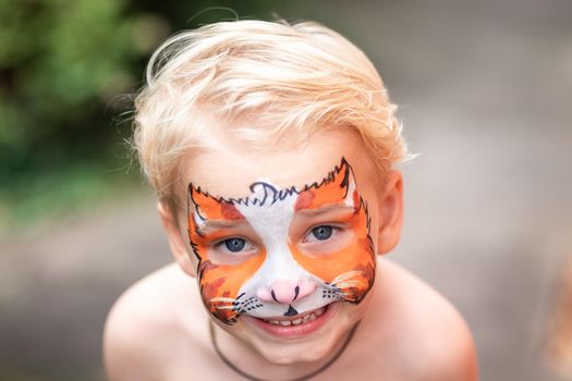 Cute little boy with face paint. Face painting, kid painting face at the birthday party or on holidays