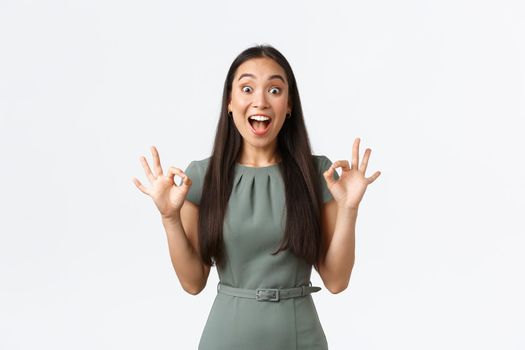 Small business owners, women entrepreneurs concept. Excited happy asian woman looking pleased and extremely thrilled, showing okay gesture and smiling astounded, white background.