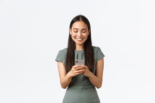 Small business owners, women entrepreneurs concept. Smiling young female running startup in internet, checking messages from clients, texting someone on mobile phone, using smartphone.