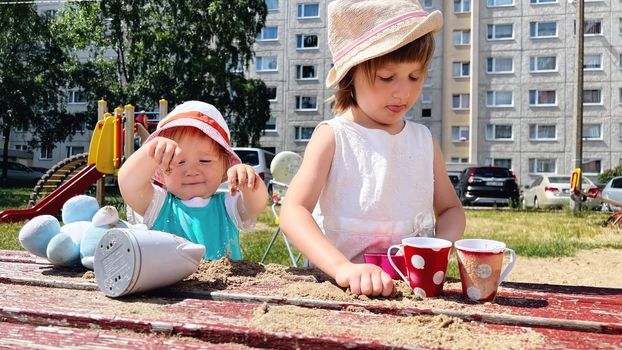 Two small girls playing with sand in the backyard of urban block houses in Tallinn, Estonia