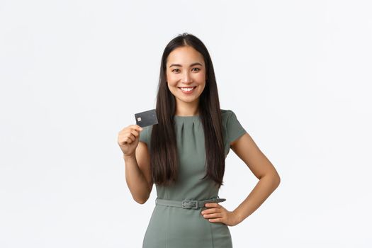 Small business owners, women entrepreneurs concept. Confident successful asian businesswoman in dress showing credit card, smiling pleased as making deposit, buying something.