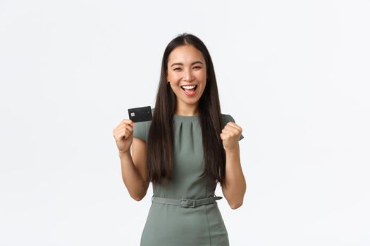 Small business owners, women entrepreneurs concept. Successful winning businesswoman, bank client in dress showing credit card and fist pump in rejoice, celebrating cashback, triumphing and smiling.