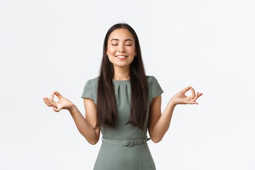 Small business owners, women entrepreneurs concept. Relaxed and peaceful smiling asian businesswoman feeling relieved after taking antidepressants, meditating, doing yoga exercise.