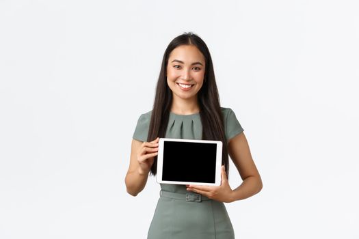 Small business owners, startup and work from home concept. Smiling attractive asian woman introduce her online store, showing application on digital tablet screen, making presentation.