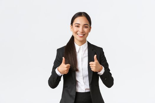 Professional confident smiling asian businesswoman assure everything going great, showing thumbs-up, recommend agency or product, like and approve, say well done, nice work or good job.