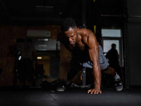 African american man doing one arm push ups in the gym