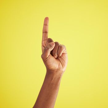 Ill do it. Studio shot of an unrecognisable man pointing upwards against a yellow background