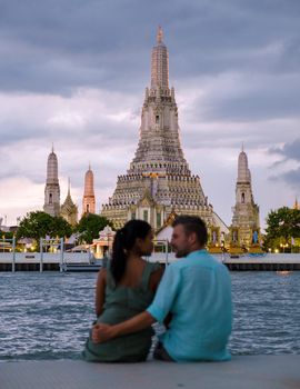 Out of focus blur couple of Asian women and European men watching the sunset at Wat Arun temple in Bangkok Thailand, Temple of Dawn, Buddhist temple alongside the Chao Phraya River.