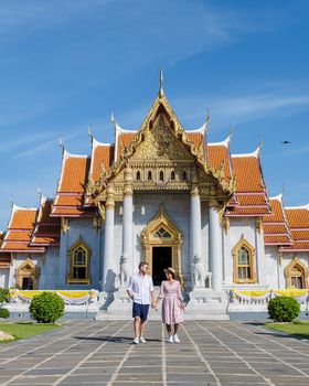 Wat Benchamabophit temple in Bangkok Thailand, The Marble temple in Bangkok. Asian woman with hat and European men visiting a temple, a couple on a city trip in Bangkok