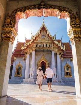 Wat Benchamabophit temple in Bangkok Thailand, The Marble temple in Bangkok. Asian woman with hat and European men visiting a temple, a couple on a city trip in Bangkok