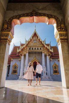 Wat Benchamabophit temple in Bangkok Thailand, The Marble temple in Bangkok. Asian woman with hat and European men visiting a temple, a couple on a city trip in Bangkok