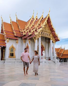 Wat Benchamabophit temple in Bangkok Thailand, The Marble temple in Bangkok. Asian woman with hat and European men visiting a temple, a couple on a city trip in Bangkok